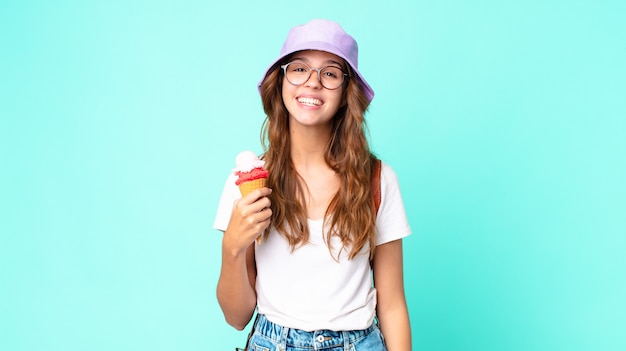 Giovane donna graziosa che sembra felice e piacevolmente sorpresa in possesso di un gelato. concetto di estate