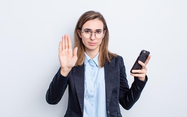 Young pretty woman looking serious showing open palm making stop gesture. business concept