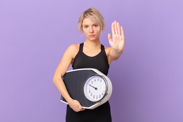 Young pretty woman looking serious showing open palm making stop gesture. diet concept