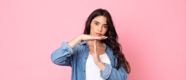 young pretty woman looking serious, stern, angry and displeased, making time out sign