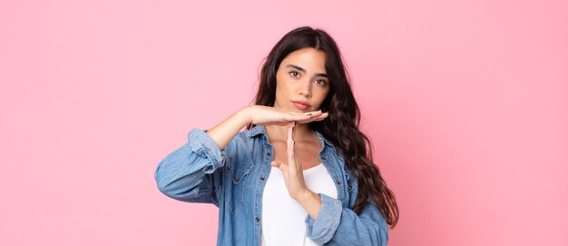 Young pretty woman looking serious, stern, angry and displeased, making time out sign