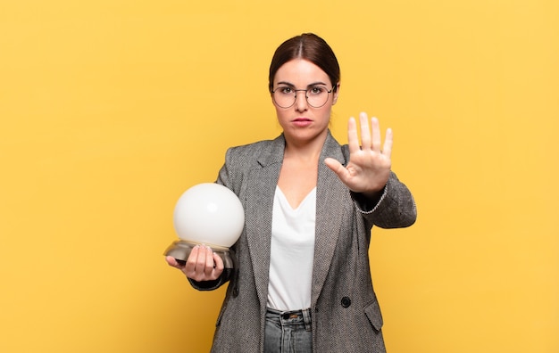 Young pretty woman looking serious, stern, displeased and angry showing open palm making stop gesture