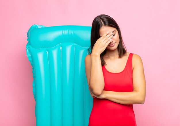 Young pretty woman looking stressed, ashamed or upset, with a headache, covering face with hand