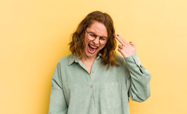 Young pretty woman looking unhappy and stressed suicide gesture making gun sign with hand pointing to head