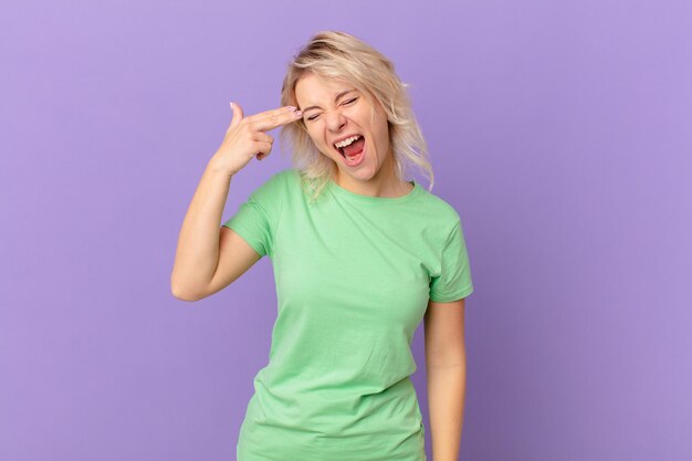 young pretty woman looking unhappy and stressed, suicide gesture making gun sign