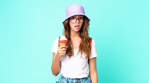 Young pretty woman looking very shocked or surprised holding an ice cream. summer concept