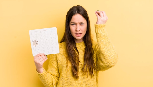 Young pretty woman making capice or money gesture telling you to pay puzzle concept