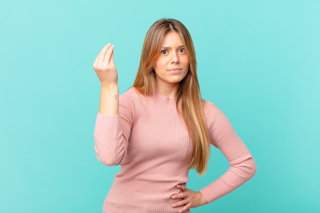 Young pretty woman making capice or money gesture, telling you to pay