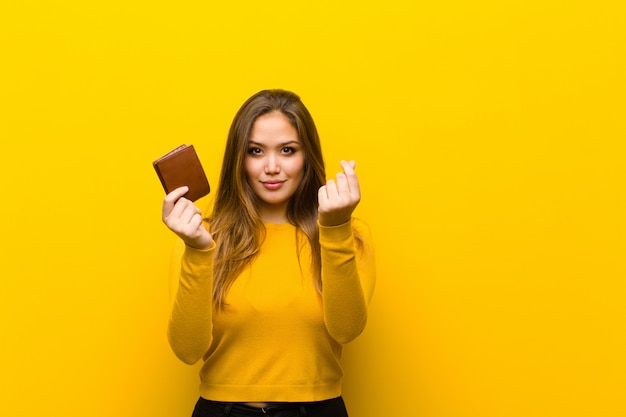 Young pretty woman money concept against orange wall