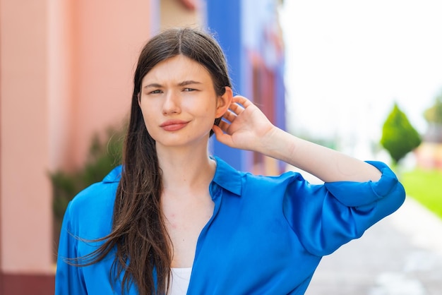 Young pretty woman at outdoors having doubts