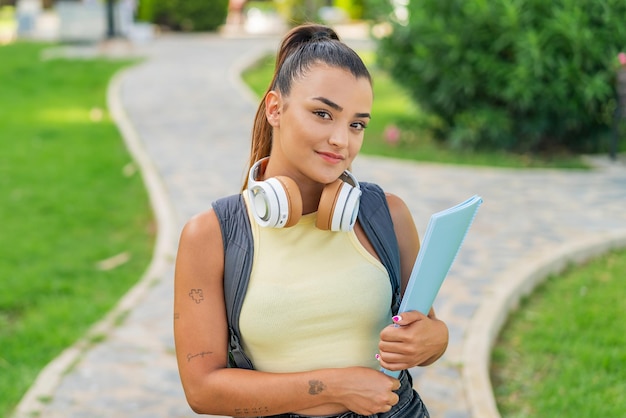 Young pretty woman at outdoors holding a notebook