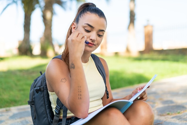 Young pretty woman at outdoors holding a notebook