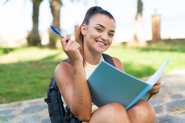 Young pretty woman at outdoors holding a notebook