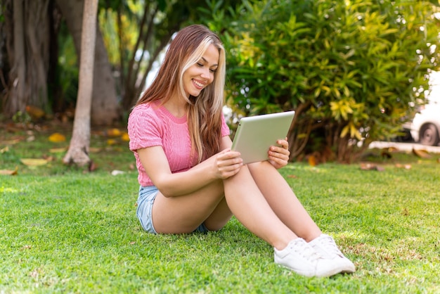 Young pretty woman at outdoors holding a tablet