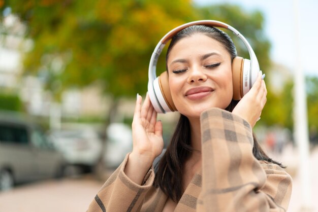 Foto giovane bella donna all'aperto che ascolta musica