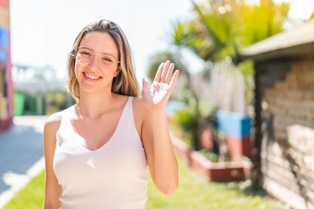 Foto giovane bella donna all'aperto che saluta con la mano con un'espressione felice