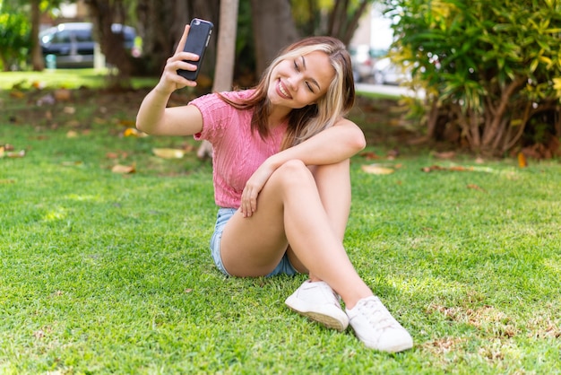 Giovane bella donna all'aperto utilizzando il telefono cellulare con espressione felice