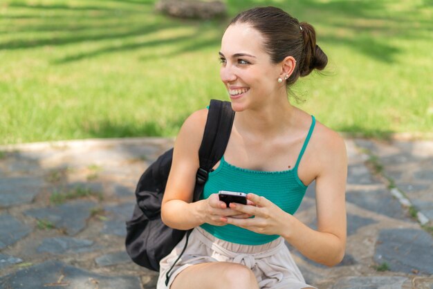 Young pretty woman at outdoors using mobile phone