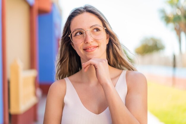 Young pretty woman at outdoors With glasses and thinking while looking up