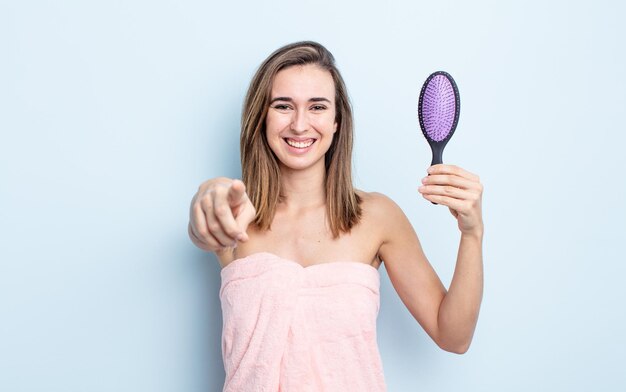 Young pretty woman pointing at camera choosing you. hairbrush concept