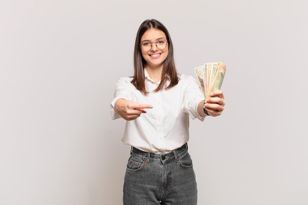 Young pretty woman pointing or showing and holding dollar banknotes