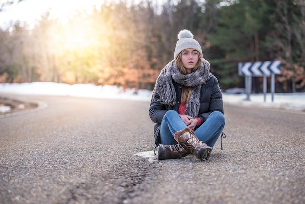 Young pretty woman on a road with snow in winter