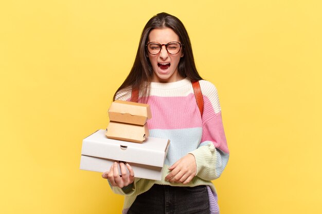 Giovane bella donna che grida in modo aggressivo, sembra molto arrabbiata, frustrata, indignata o infastidita, urlando no. prendi un concetto di fast food