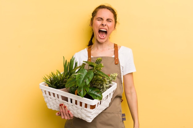 Young pretty woman shouting aggressively looking very angry plants concept