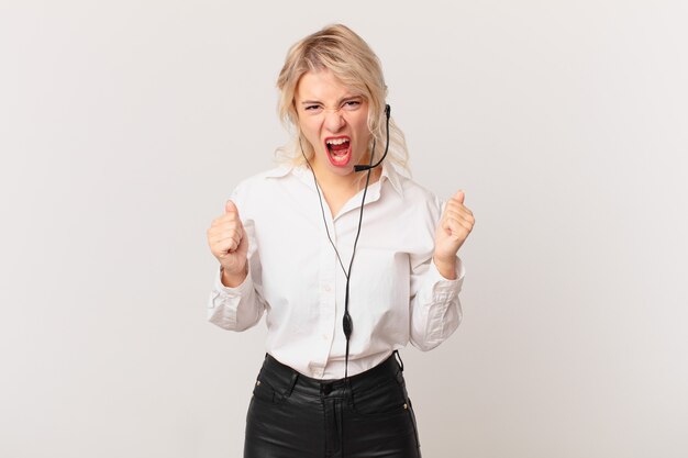 Young pretty woman shouting aggressively with an angry expression. telemarketing concept