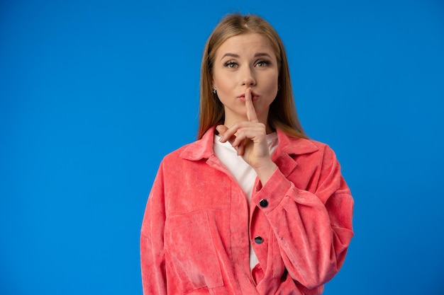 Young pretty woman showing silence gesture over blue background