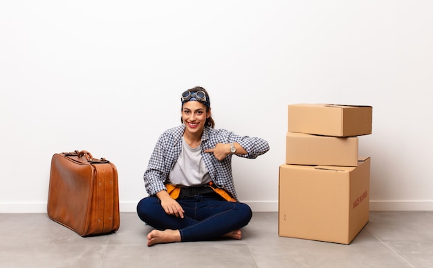 Young pretty woman sitting with boxes and a suitcase