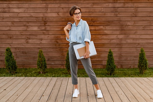 Young pretty woman sitting with laptop in modern park street