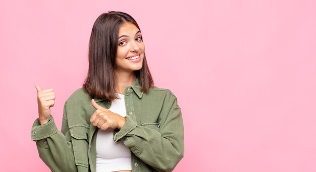 陽気でさりげなく横のコピースペースを指して、幸せで満足している若いきれいな女性