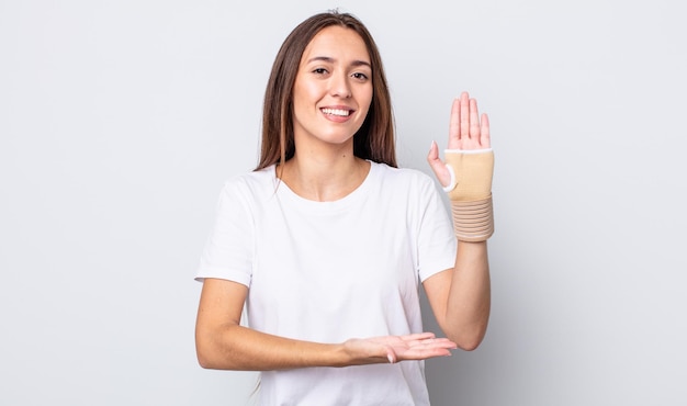 Young pretty woman smiling cheerfully, feeling happy and showing a concept. hand bandage concept