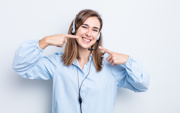 Young pretty woman smiling confidently pointing to own broad smile. telemarketer concept