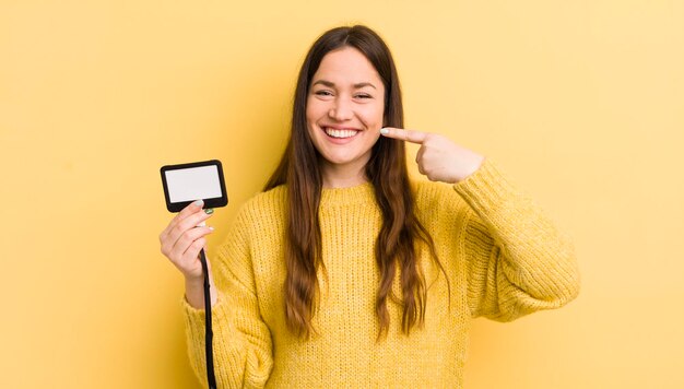 Young pretty woman smiling confidently pointing to own broad\
smile vip pass concept