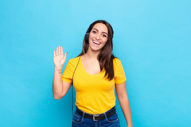 Young pretty woman smiling happily and cheerfully, waving hand