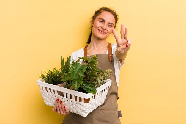 笑顔でフレンドリーに見える若いきれいな女性は、3番目の植物の概念を示しています