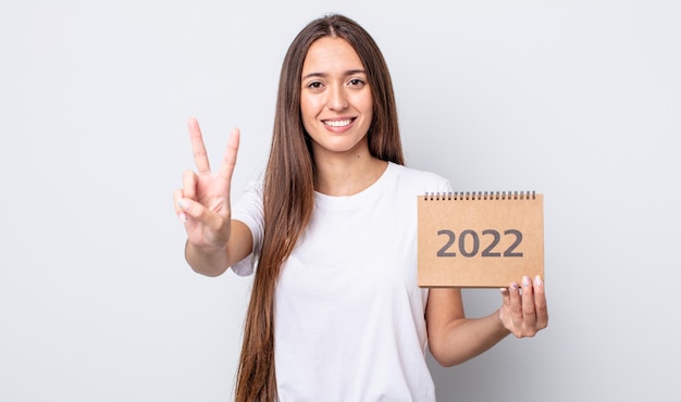 Foto giovane donna graziosa che sorride e che sembra amichevole, mostrando il numero due. 2022 concetto di pianificatore