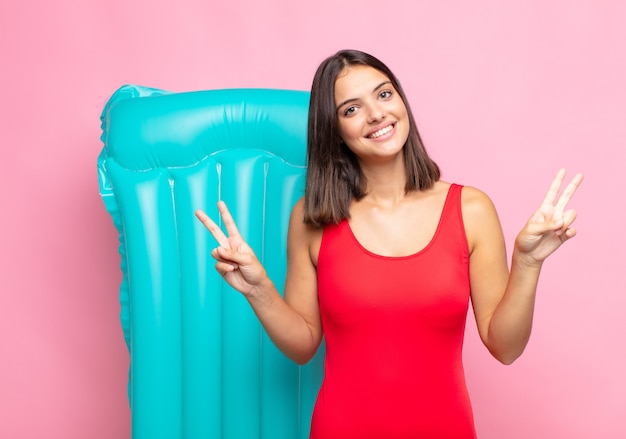 Young pretty woman smiling and looking happy, friendly and satisfied, gesturing victory or peace with both hands