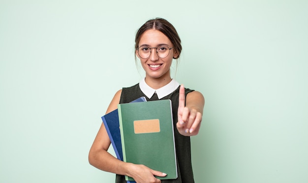 誇らしげに、自信を持って笑顔の若いきれいな女性がナンバーワンになります。大学の概念