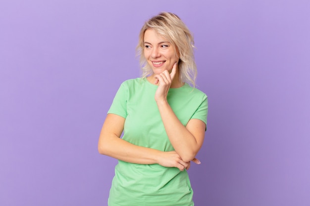 Young pretty woman smiling with a happy, confident expression with hand on chin