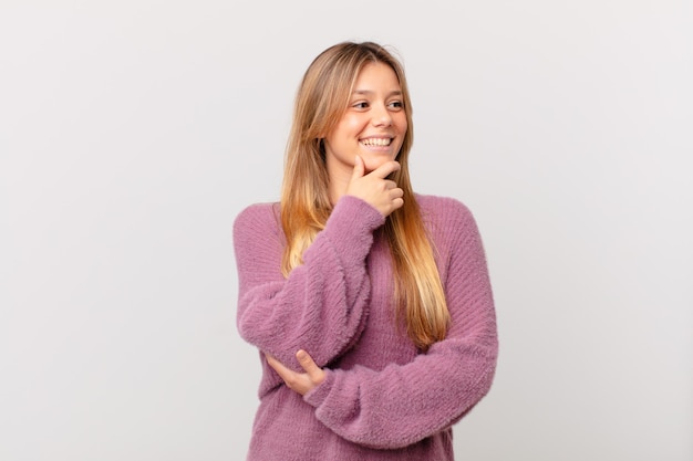 Young pretty woman smiling with a happy confident expression with hand on chin