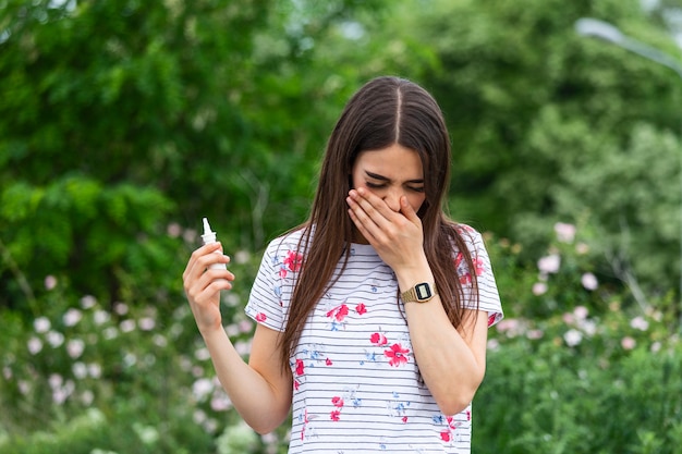 Photo young pretty woman sneezing in front of blooming tree.