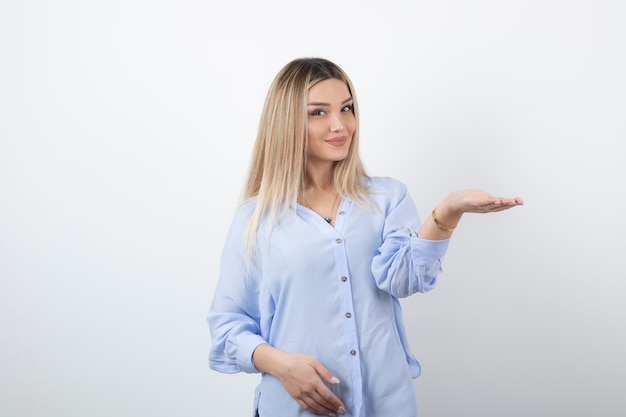 Young pretty woman standing and posing on white wall.