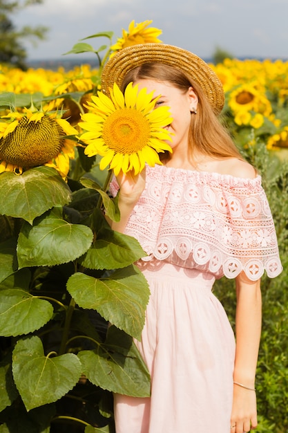 Young pretty woman stands among blooming sunflowers