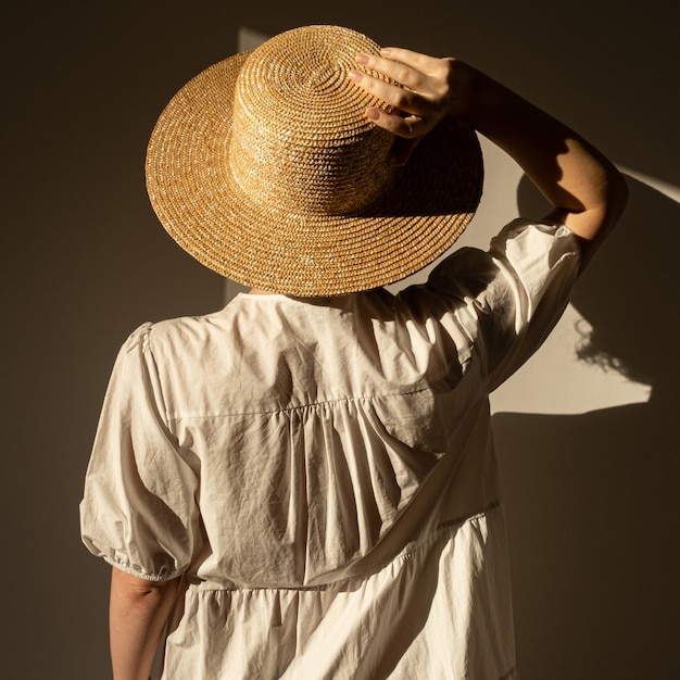 Giovane donna graziosa in cappello di paglia e prendisole vestito bianco