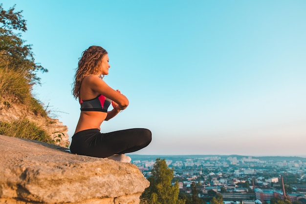 Giovane donna graziosa sull'esercizio di yoga all'alba