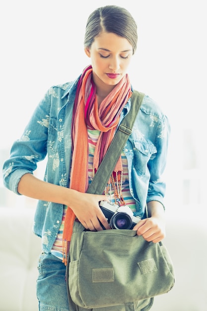 Foto giovane donna graziosa che cattura la macchina fotografica dalla sua borsa