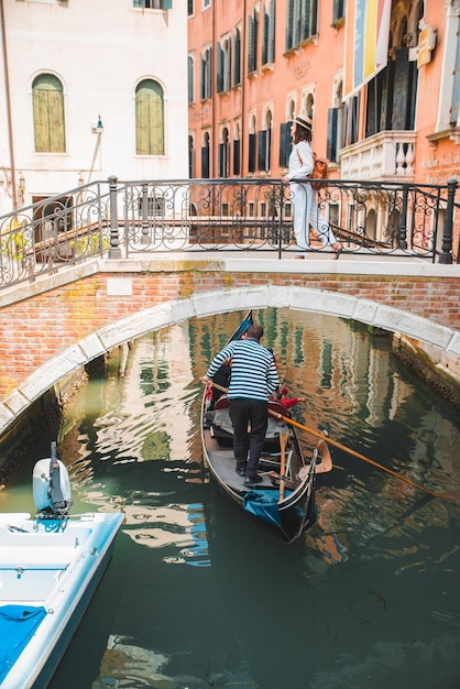 Young pretty woman traveler standing at venice bridge cross canal gondolas in water